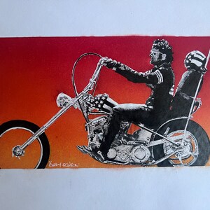 May include: A black and white illustration of a motorcycle with a rider and a passenger. The motorcycle is a chopper with a long front fork and a large rear tire. The rider is wearing a leather jacket and sunglasses. The passenger is wearing a helmet. The background is a gradient of orange and red. The text "Easy Rider" is written below the motorcycle.