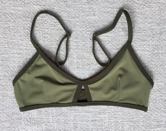 May include: A green bikini top with a V-neck and a cut-out detail in the front.