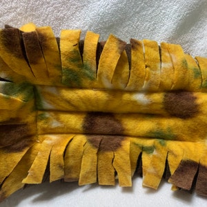 Può includere: Un giocattolo per cani in pile giallo, marrone e verde con stampa a girasole e frange.