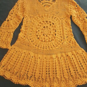 May include: A mustard yellow crocheted top with long sleeves and a round, lacy design in the center.