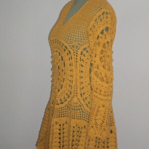 May include: A yellow crocheted dress with long sleeves and a flared skirt.