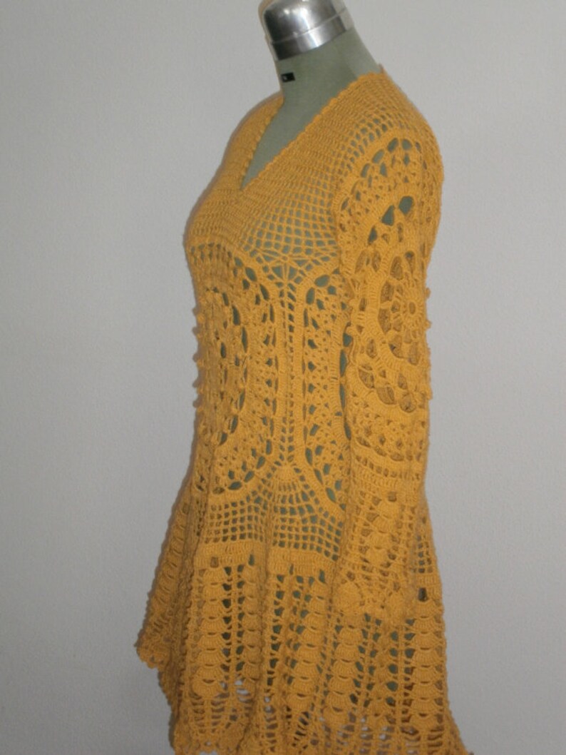 May include: A yellow crocheted dress with long sleeves and a flared skirt.
