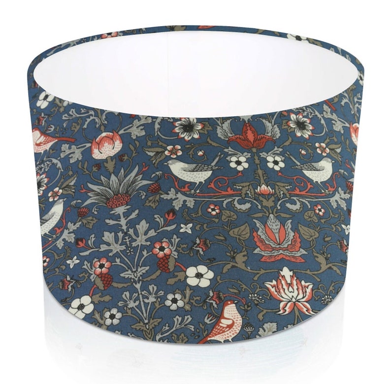 Pode incluir: Abajur cil&iacute;ndrico com fundo azul com um padr&atilde;o repetido de p&aacute;ssaros, flores e folhagens em vermelho, branco e cinza. O interior do abajur &eacute; branco.