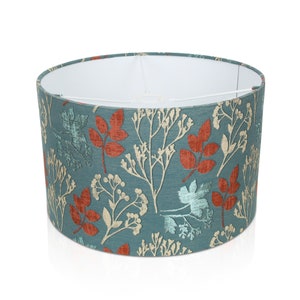 May include: A teal blue lampshade with a floral pattern featuring red, orange, and cream leaves and branches.