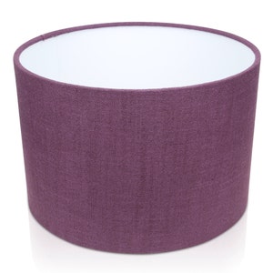 May include: A purple fabric lampshade with a white interior. The lampshade is cylindrical and has a textured fabric surface.