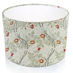 Pode incluir: Abajur cil&iacute;ndrico com um padr&atilde;o floral de flores vermelhas e amarelas, folhas verdes e caules cinzentos sobre um fundo creme. O interior &eacute; branco. Adequado para candeeiros de mesa ou de p&eacute;.