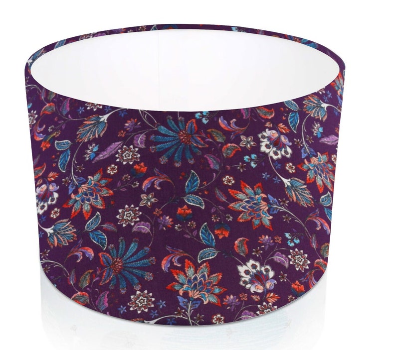 Pode incluir: Abajur cil&iacute;ndrico com um padr&atilde;o floral. A sombra apresenta um fundo roxo escuro com um design repetido de flores estilizadas em tons de verde-azulado, vermelho e branco. O interior &eacute; branco.