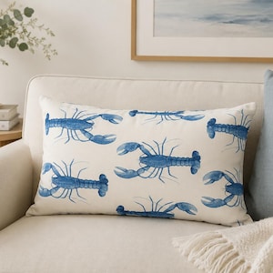 May include: A rectangular throw cushion featuring a repeating pattern of blue lobster illustrations on an off-white fabric background. The design displays multiple lobsters oriented in various directions across the surface of the cushion cover.