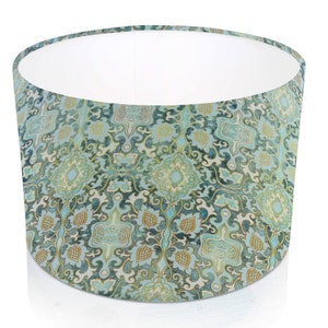 Pode incluir: Abajur cil&iacute;ndrico com um padr&atilde;o floral detalhado em tons de turquesa, azul e dourado. O interior &eacute; branco, contrastando com o design intrincado. O abajur foi projetado para difundir a luz.