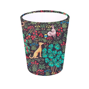 May include: A black cylindrical lampshade with a white interior. The lampshade features a repeating pattern of stylised flowers, leaves, a rabbit, and a dog on a black background.