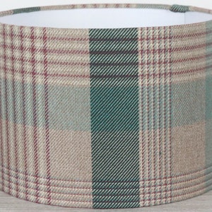 May include: A cylindrical lampshade with a plaid pattern in shades of brown, green, and pink.