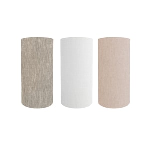 May include: Three cylindrical lamp shades in neutral colours. The shades are arranged side by side against a white background. The shades are in beige, white, and a textured tan colour.