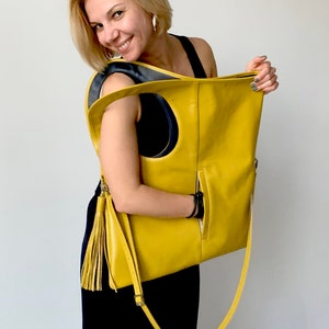 Yellow leather bag is finished with an outside vertical zipper pocket and a strap. The bag is fully lined and has two inner pockets. The bag can be carried on the shoulder or crossbody. Height 20.5 Width 18.5 inches.