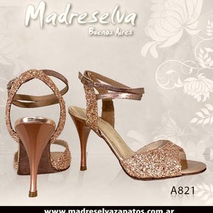 May include: A pair of rose gold glitter high-heeled sandals with ankle straps and a metallic finish on the heel. The text Madreselva Buenos Aires and A821 are visible. The website www.madreselvazapatos.com.ar is printed at the bottom of the image.