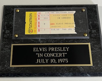 May include: A black and gold plaque with a Ticketron ticket for Elvis Presley's "In Concert" on July 10, 1975 at The Coliseum. The ticket is for seat 7, row H, section 231. The plaque reads "Elvis Presley "In Concert" July 10, 1975".