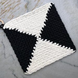 May include: Black and white crocheted pot holder with a wooden ring handle.