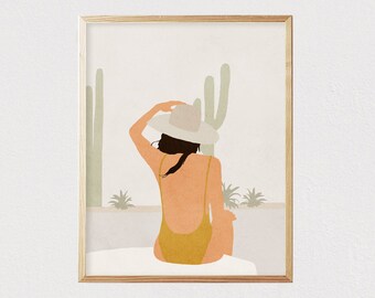 May include: A woman wearing a yellow swimsuit and a white hat sits in front of a desert landscape with cacti.