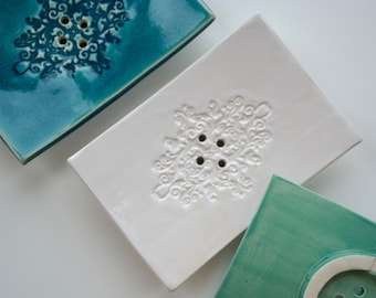 Vierkant keramisch zeepbakje van 11 x 7 cm met afwateringsgaten en een symmetrisch patroon.