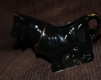 黒地に金色の縁取りが施された牛の形をしたクリーマー