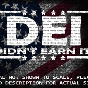 May include: A decal with a distressed American flag design in the background. The words "DEI DIDN'T EARN IT!" are in white block letters. The text "DECAL NOT SHOWN TO SCALE, PLEASE READ DESCRIPTION FOR ACTUAL SIZE!" is at the bottom.