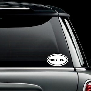 May include: A black car with a white oval sticker on the back window. The sticker says "YOUR TEXT".