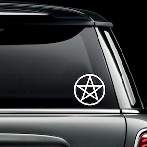May include: White vinyl decal of a pentagram inside a circle, affixed to the rear window of a black vehicle. The design is a simple, clean graphic, suitable for car decoration. The sticker is a symbol of Wicca and Paganism.