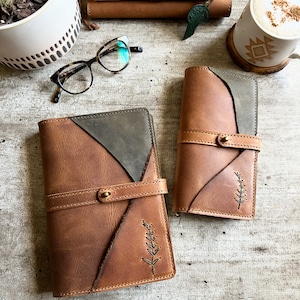 May include: Two brown leather journals with green accents and a simple plant design. The journals have a strap closure and are made of high-quality leather.