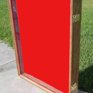 May include: A wooden display case with a red velvet interior and brass hinges. The case has a glass front and is closed.