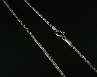 Könnte beinhalten: Eine silberne Kettenkette mit einem Karabinerverschluss. Die Kette besteht aus kleinen, miteinander verbundenen, runden Perlen.
