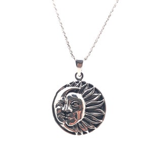 May include: A silver necklace with a round pendant featuring a detailed design of a sun and moon.