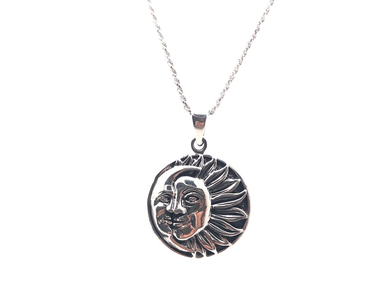 May include: A silver necklace with a round pendant featuring a detailed design of a sun and moon.