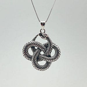 May include: Silver snake pendant necklace with a knot design. The snake is intertwined with itself, creating a complex and intricate pattern.