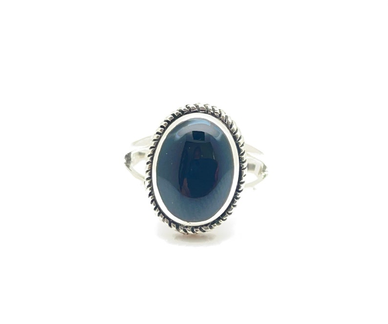 May include: A silver ring with a black oval gemstone set in a decorative silver bezel.