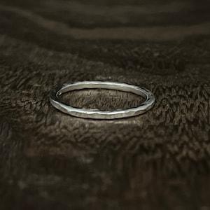 May include: A silver hammered ring with a smooth, polished finish. The ring is simple and elegant, and would make a great everyday piece of jewelry.