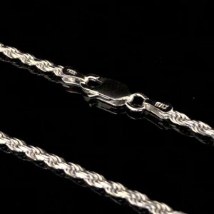 May include: A silver rope chain necklace with a lobster clasp closure. The chain is made of a twisted rope design.