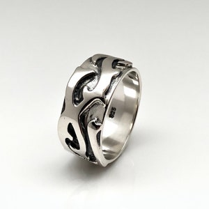 May include: A silver ring with a textured, abstract design. The ring is marked with "925" on the inside band.