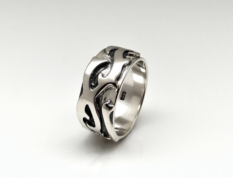 May include: A silver ring with a textured, abstract design. The ring is marked with "925" on the inside band.