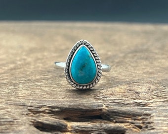 May include: A teardrop-shaped turquoise gemstone ring set in sterling silver with a rope-like border.