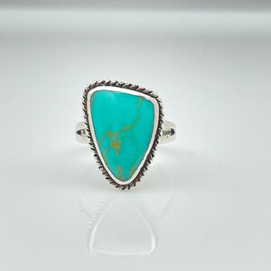 May include: A turquoise ring with a silver setting. The turquoise is a light blue color with brown veins running through it. The ring is a size 7.