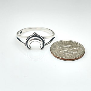 Peut inclure: Une bague argent&eacute;e orn&eacute;e d'un croissant de lune avec une bordure perl&eacute;e. Une pi&egrave;ce de monnaie est &agrave; c&ocirc;t&eacute; de la bague pour comparaison de taille. La bague a un th&egrave;me c&eacute;leste.