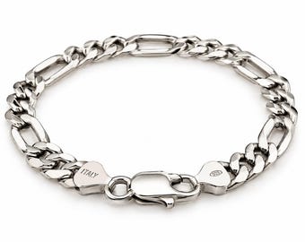May include: A silver Figaro chain bracelet featuring a lobster claw clasp. The metal links are polished and reflective. One end tag is stamped with the word ITALY, and the other end tag is stamped with the number 925, indicating sterling silver.