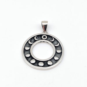 May include: Silver pendant featuring a circular design with a central open circle and a series of crescent moons around the outer edge.