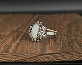 Könnte beinhalten: Ein silberner Ring mit einem ovalen Opal-Edelstein, der in einem filigranen Design gefasst ist.