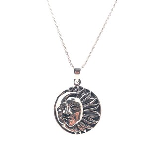 May include: A silver necklace with a round pendant featuring a detailed design of a sun and moon.
