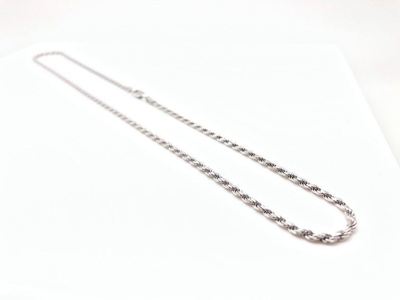 May include: A silver rope chain necklace. The chain is made of a twisted rope design.