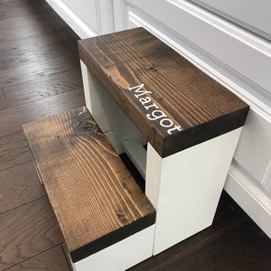 Large wooden step stool, dark walnut stained steps with white painted supports, personalized name hand painted on step, step stool in a kitchen, step stool against cabinet, kids step stool, modern style