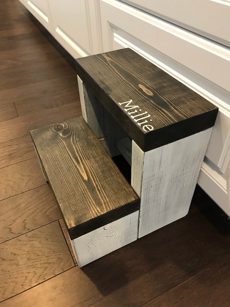 Large wooden step stool, ebony stained steps with rustic white painted supports, personalized name hand painted on step, step stool in a kitchen, step stool against cabinet, kids step stool, modern style