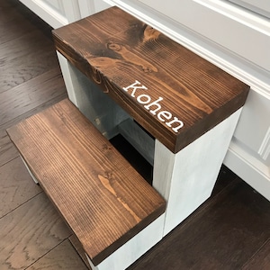 Large wooden step stool, dark walnut stained steps with rustic white painted supports, personalized name hand painted on step, step stool in a kitchen, step stool against cabinet, kids step stool, modern style