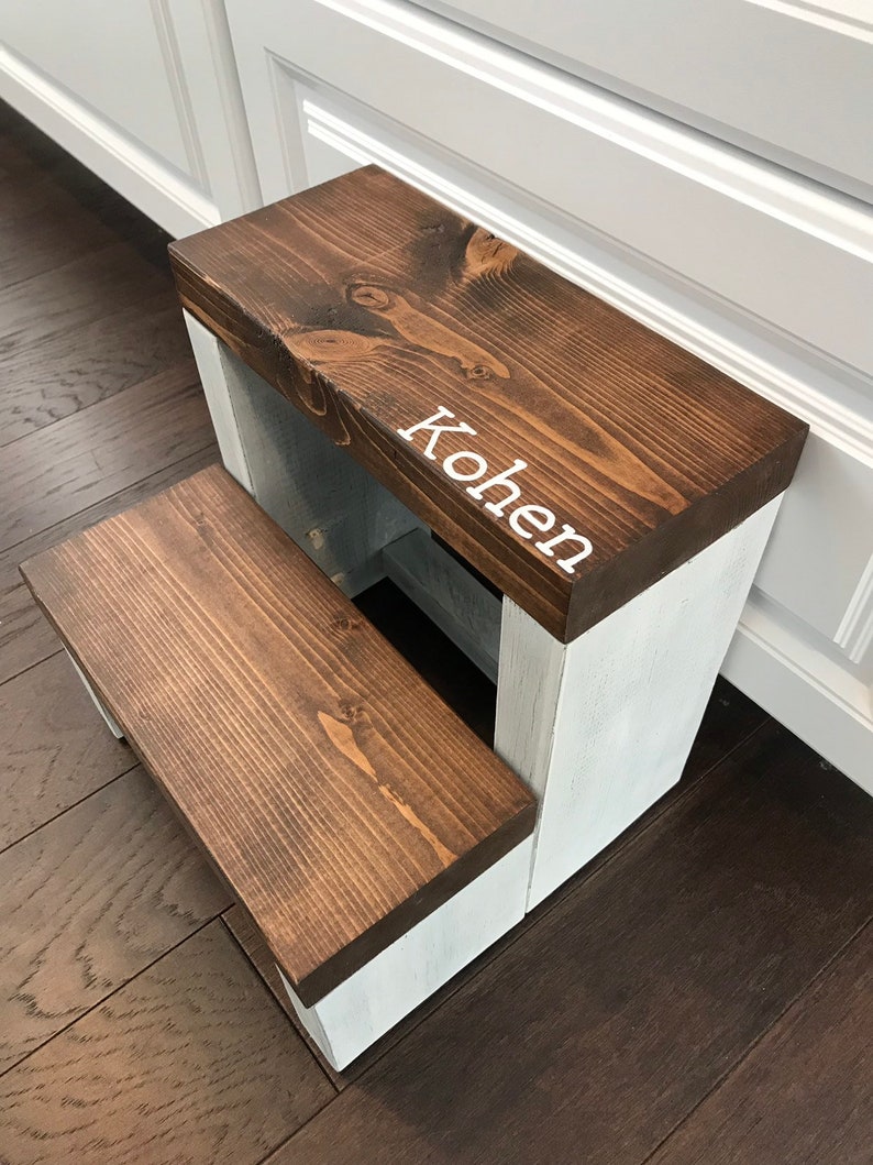 Large wooden step stool, dark walnut stained steps with rustic white painted supports, personalized name hand painted on step, step stool in a kitchen, step stool against cabinet, kids step stool, modern style