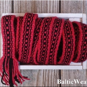 Op de afbeelding: Rode en zwarte geweven trim met een geometrisch patroon. De trim zit in een houten doos met de tekst "Baltic Weaver" op de bodem.